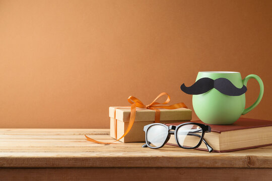 Happy Fathers day concept with green coffee cup, mustache, book and gift box on wooden table