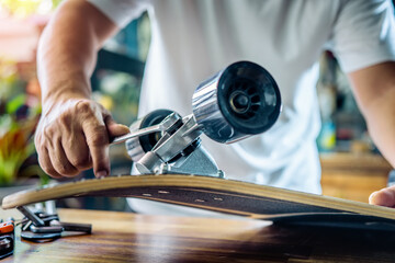 man use the socket tool to remove the nuts on skateboard and adjusts suspension in workshop, Skateboard maintenance and repair concept. Selective focus on suspension set