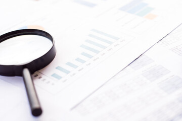 Closeup of magnifying glass on paper background with business chart