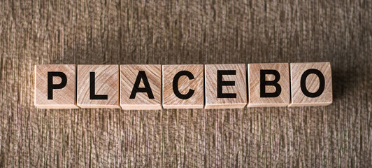 Placebo word written on blocks on wooden surface. Placebo effect, fake medical treatment - obrazy, fototapety, plakaty