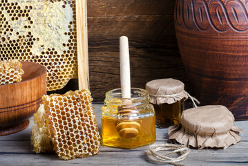 Honey in jar with honey dipper on wooden background.