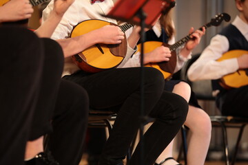 A balalaika in the hands of a young musician playing in a group of teenagers in a folklore...
