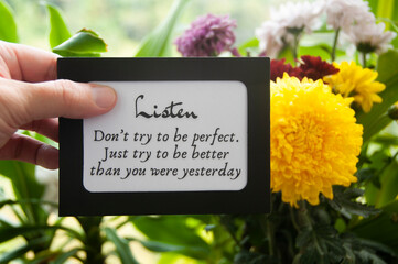 Hand holding notepad with motivational quote - Don't try to be perfect. Just try to be better than...