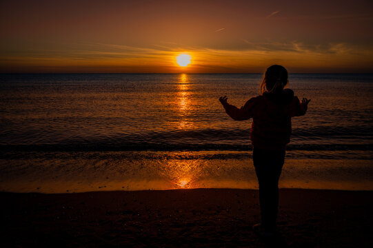 Mädchen spielt am Strand bei Sonnenuntergang