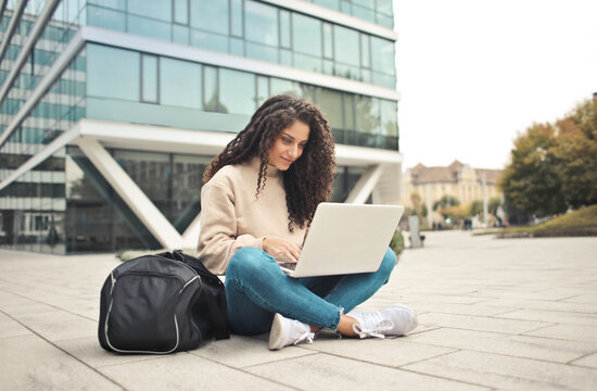 young woman with gym bag and computer in the street