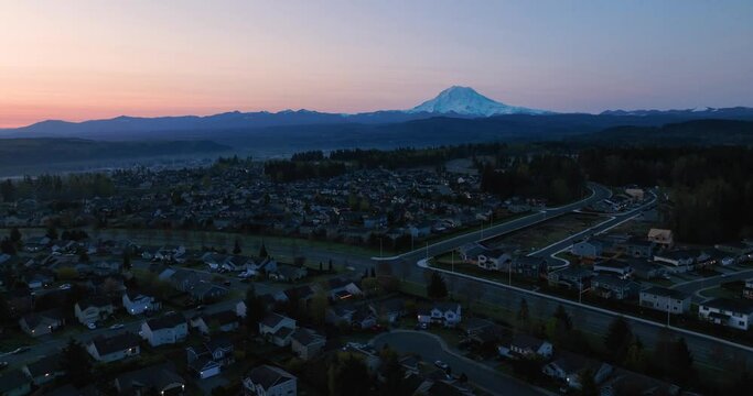 Wide orbiting aerial of a Puyallup neighborhood nestled under the looming presence of Mount Rainier at sunrise.