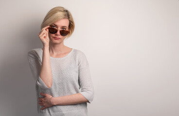 Portrait of a beautiful young girl with sunglasses on a gray background