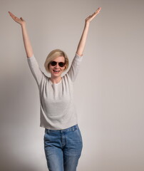Beautiful and happy young woman with sunglasses
 on gray background with arms open