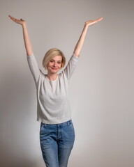 Beautiful and happy young woman on gray background with arms open