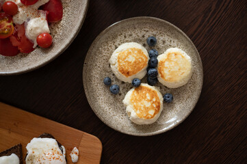 Cheese pancakes with blueberries in plate on dark table