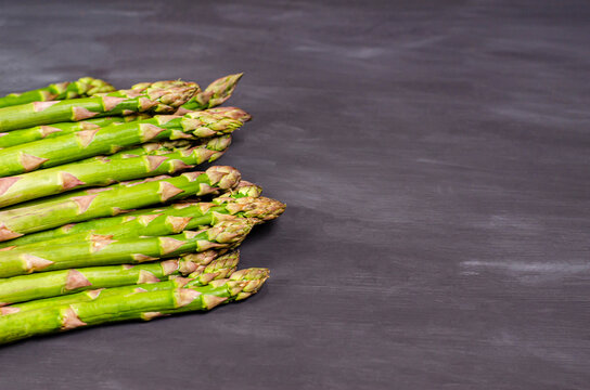 Stems of fresh green asparagus on a black background with place for text