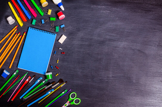 Various office supplies and a notebook on a black background.