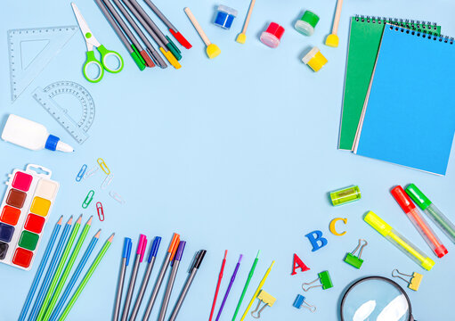 A variety of stationery, notebook, paints, felt-tip pens, markers on a blue background.