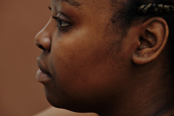 Side view of African young woman face looking away isolated on brown background