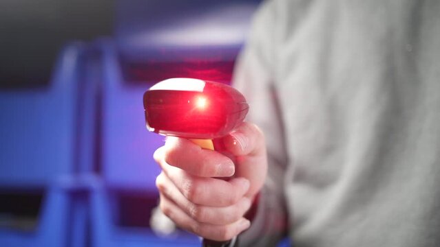 Holding a Red Laser Bar Code Scanner in a Warehouse Closeup