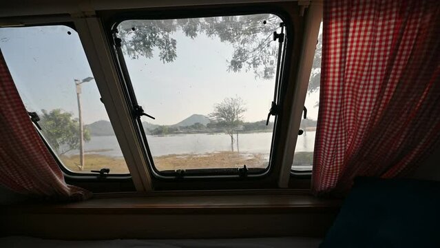 Inside of empty bedroom of motor home and the view through window on lakeside in the morning