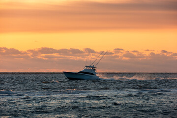 A fishing vessel navigating the Oregon Inlet against a sunrise sky, Outer Banks North Carolina