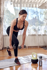 Fototapeta na wymiar Pretty woman working out at home. Adult lady with beautiful shaped body exercising in the apartment.