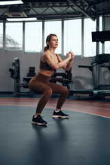 Obraz na płótnie Canvas Pretty woman working out in a gym. Adult lady with beautiful shaped body.