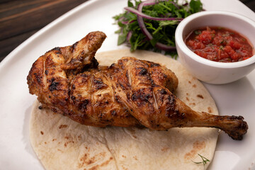 Grilled chicken half with sauce and herbs
