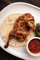 Grilled chicken half with sauce and herbs