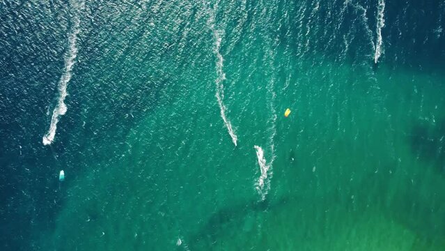 Aerial drone view of windsurfers and kite surfers enjoying on blue sea ocean waves.	
