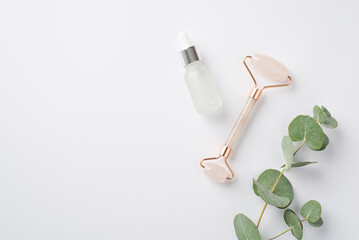 Top view photo of eucalyptus rose quartz roller and glass bottle on isolated white background with copyspace