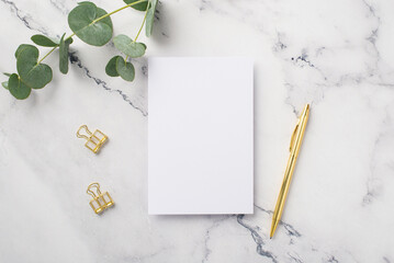 Business concept. Top view photo of paper sheet gold pen binder clips and eucalyptus on white...