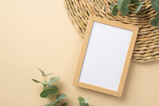 Top view photo of wooden photo frame eucalyptus and decorative placemat on isolated beige background with blank space