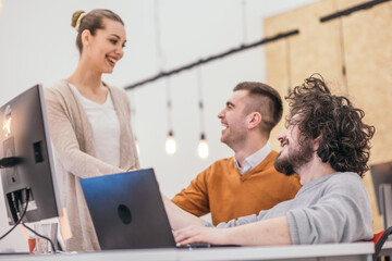 Obraz premium Coworkers, employees working and discussing a project they are preparing while typing on a laptop and looking at pc, computer.