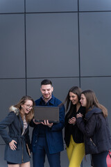 Fototapeta premium Looking at the lap top and laughing all together while standing outside