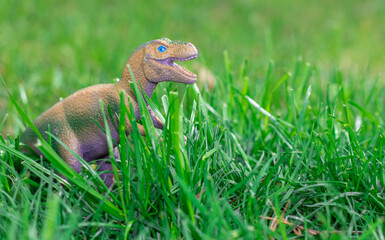 some dinosaurs toys in the green grass. happy dinosaur day, may 15 and june 1. fascinating dinosaur fantasies. spring summer outside, public park, kids having fun