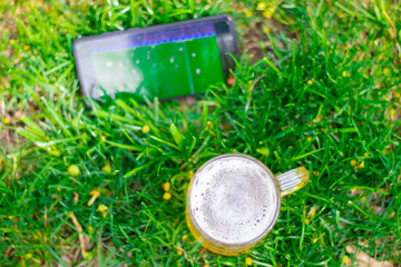 glass of beer on green grass in public park, green nature, spring, summer.
mobile phone,smartphone, with football match playing, football fans, on the go, big fan, idols.