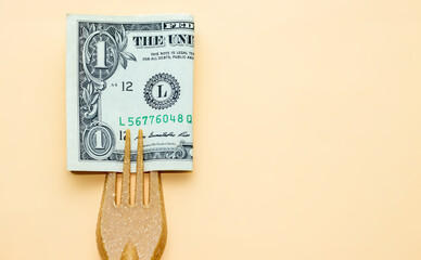 one dollar bill in the tines of a fork made from recycled materials on light orange background....