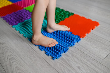 The child walks on an orthopedic massage mat for feet. Massage mats with different stiffness and...