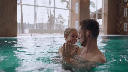 happy father and his little daughter is swimming together in pool of modern new wellness center - Powered by Adobe