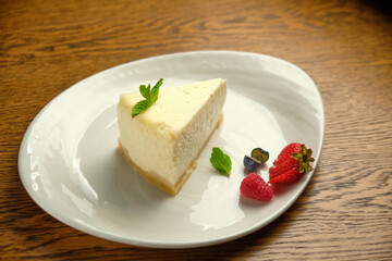 A piece of cheesecake, a classic New York-style cheesecake on a wooden table
