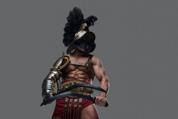 Glorious ancient warrior dressed in combative suit holding two swords against grey background.