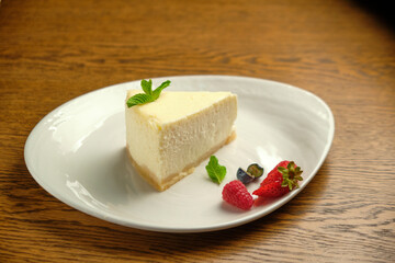 A piece of cheesecake, a classic New York-style cheesecake on a wooden table