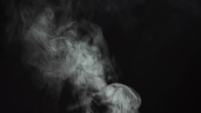 Abstract smoke on black chroma key background. Smoking in darkness, steam clouds close-up.