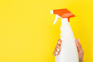 Cleaner's hand holding a  chemical spray bottle. Empty space for text or logo on a yellow...