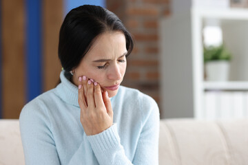 Woman holding her cheek in area of sore tooth
