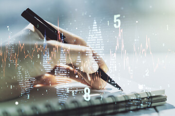 Abstract creative financial graph with hand writing in notebook on background, forex and investment...