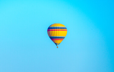 Fototapeta na wymiar Colorful balloon flying over a clear blue sky during a sunset on a sunny day in Cappadocia, Turkey, copy space