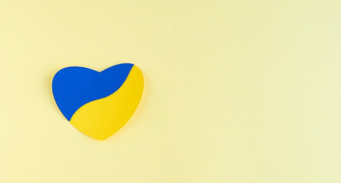 Heart cut out of paper with Ukrainian flag colors on yellow background. Copy space. - Powered by Adobe