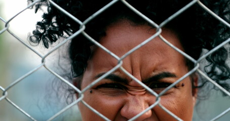 Angry upset african woman yelling seen through metal fence barrier