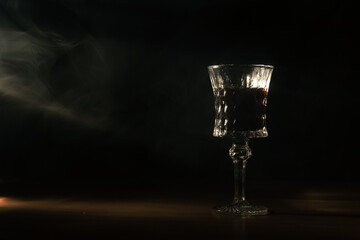 rays of light fall on a classic glass of wine. dark room