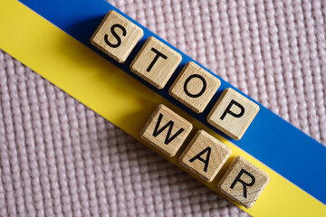Stop war written on wooden cubes on background of ukrainian flag closeup