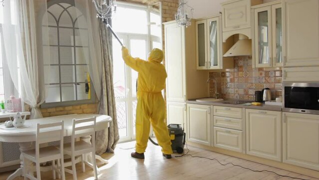 a man from a cleaning company in quarantine, dressed in a protective suit, cleans the house with a vacuum cleaner