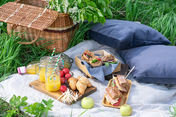 picnic basket, croissants, sandwiches, orange juice. Vertical